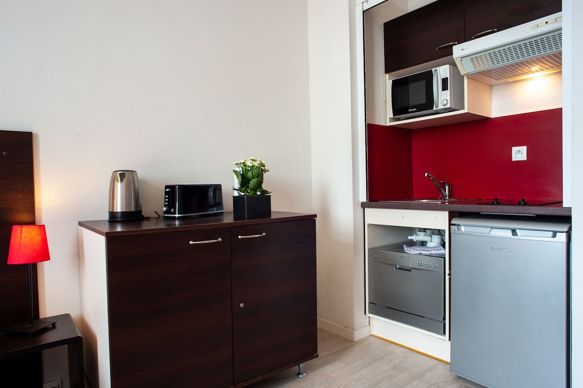 Een kleine keuken met een magnetron, een koelkastje en een kast met lades.