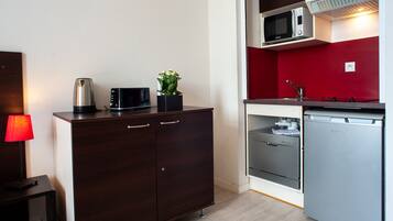 A compact kitchenette with a microwave, a small refrigerator, and a cabinet with drawers.