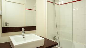 A bathroom with a white sink, a mirror, and a glass-enclosed shower.