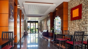 Eine moderne Lobby mit Empfangstresen, Sitzgelegenheiten und einer Treppe zu den oberen Etagen.