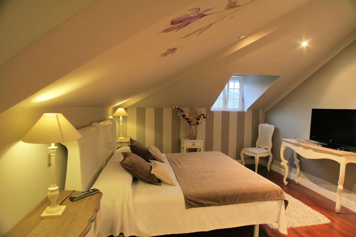 Un dormitorio con cama, lámparas de noche, televisión, escritorio y silla.