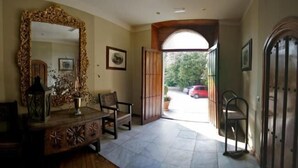 A spacious room with a large mirror, a wooden cabinet, a chair, and a door leading to a covered outdoor area.