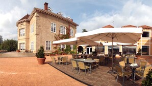 An outdoor patio area with tables and chairs, surrounded by buildings with a traditional architectural style.