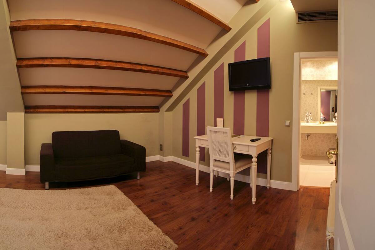 Un dormitorio con una cama, un escritorio, una silla, un sofá y una televisión.