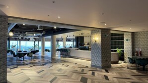 A modern interior with a herringbone floor pattern, a bar area, and seating arrangements. - Waterfront Southport Hotel (Southport)