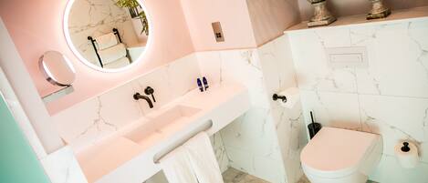 A modern bathroom with a marble sink, a toilet, and a mirror with a light.