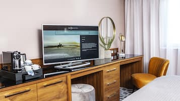 Una habitación de hotel con escritorio de madera, televisor de pantalla plana, cafetera y cama cómoda.