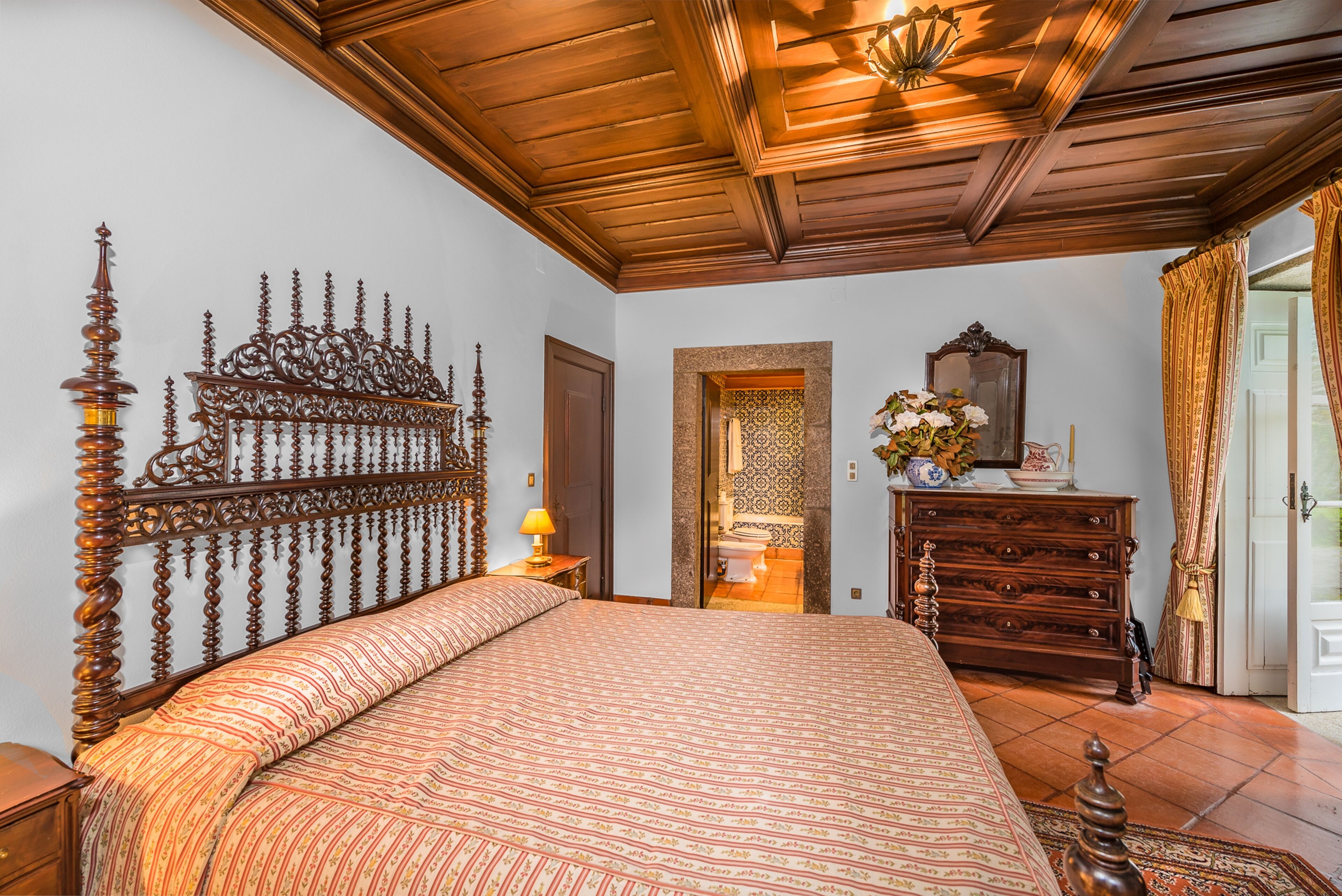 Un dormitorio con una cama grande, cabecera de madera, un aparador y un espejo.