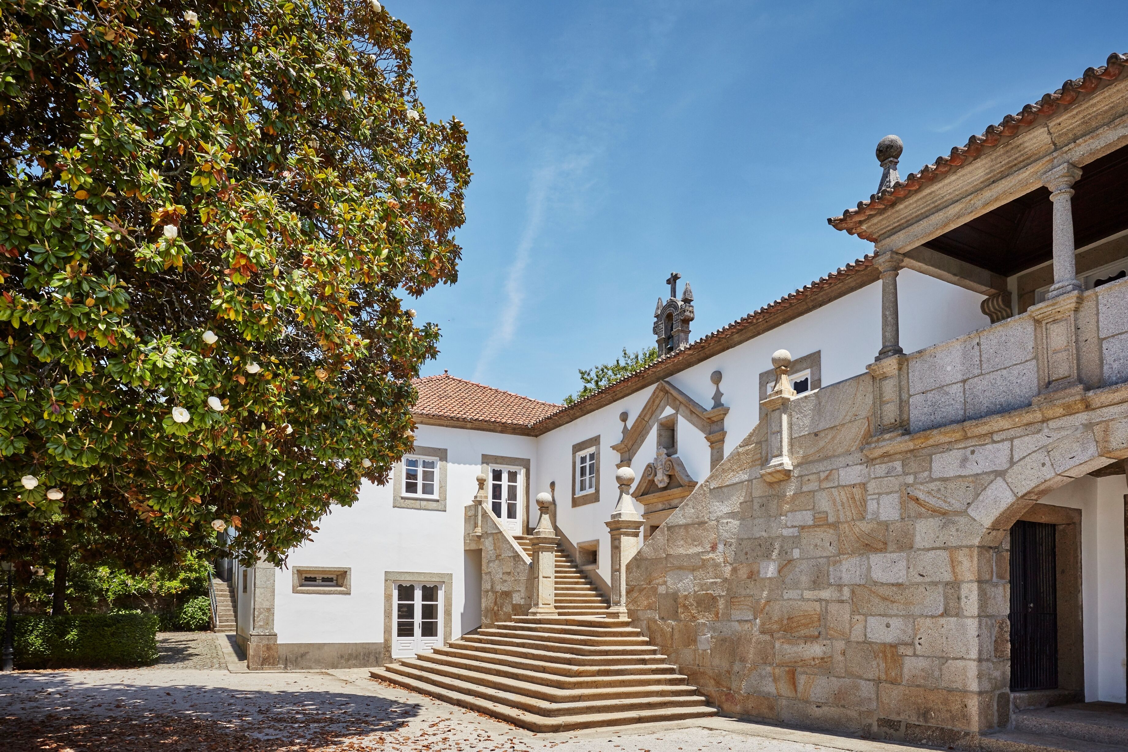A building with a stone staircase leading to a door, surrounded by trees and a clear sky.