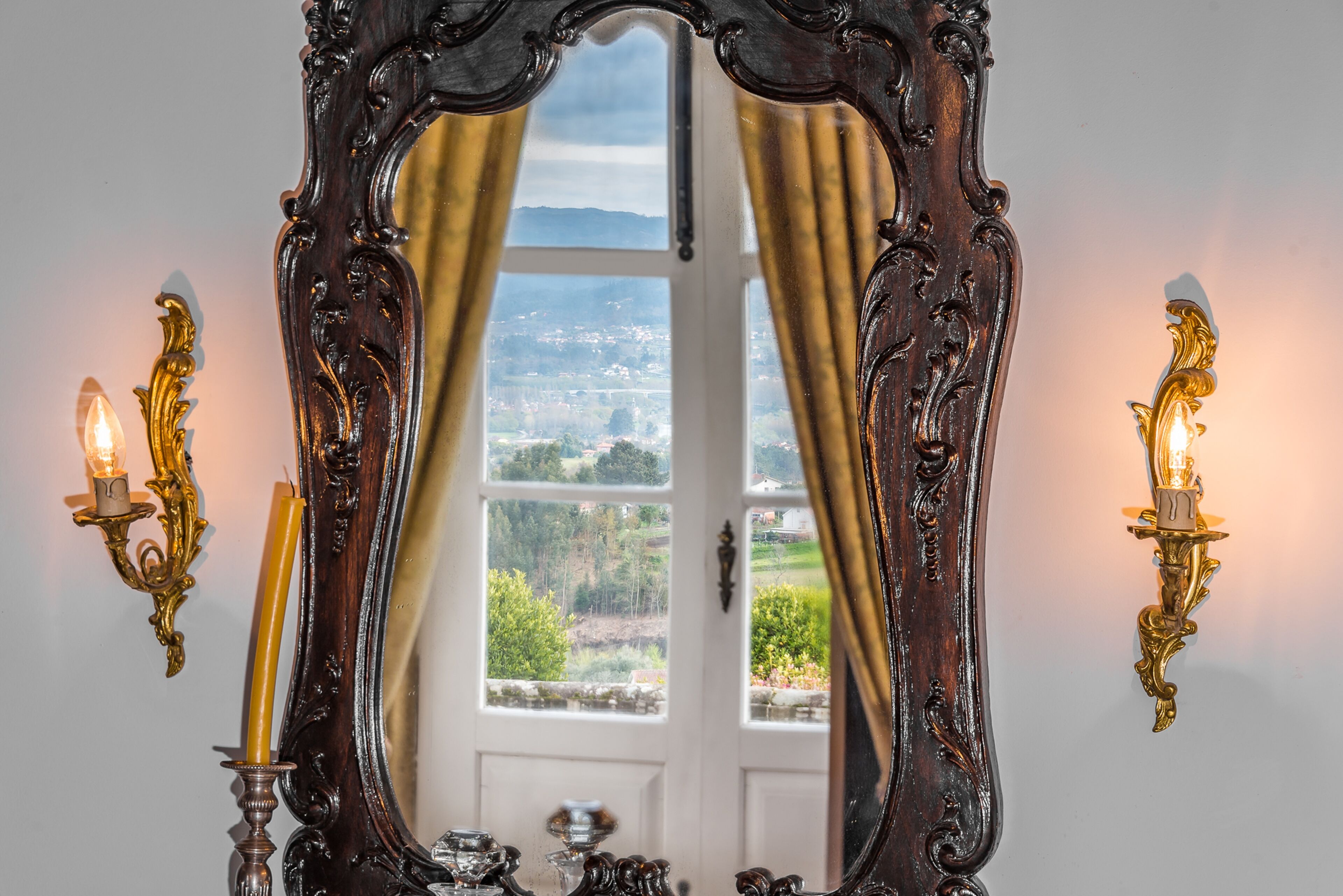 Ein kunstvoller Spiegel mit Blick auf eine Landschaft durch ein Fenster.