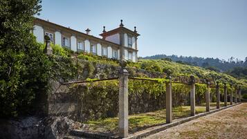 A historic building with a stone wall and a vine-covered trellis.