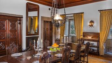 Une salle à manger élégante, avec une table en bois dressée pour le repas, entourée de chaises richement décorées.