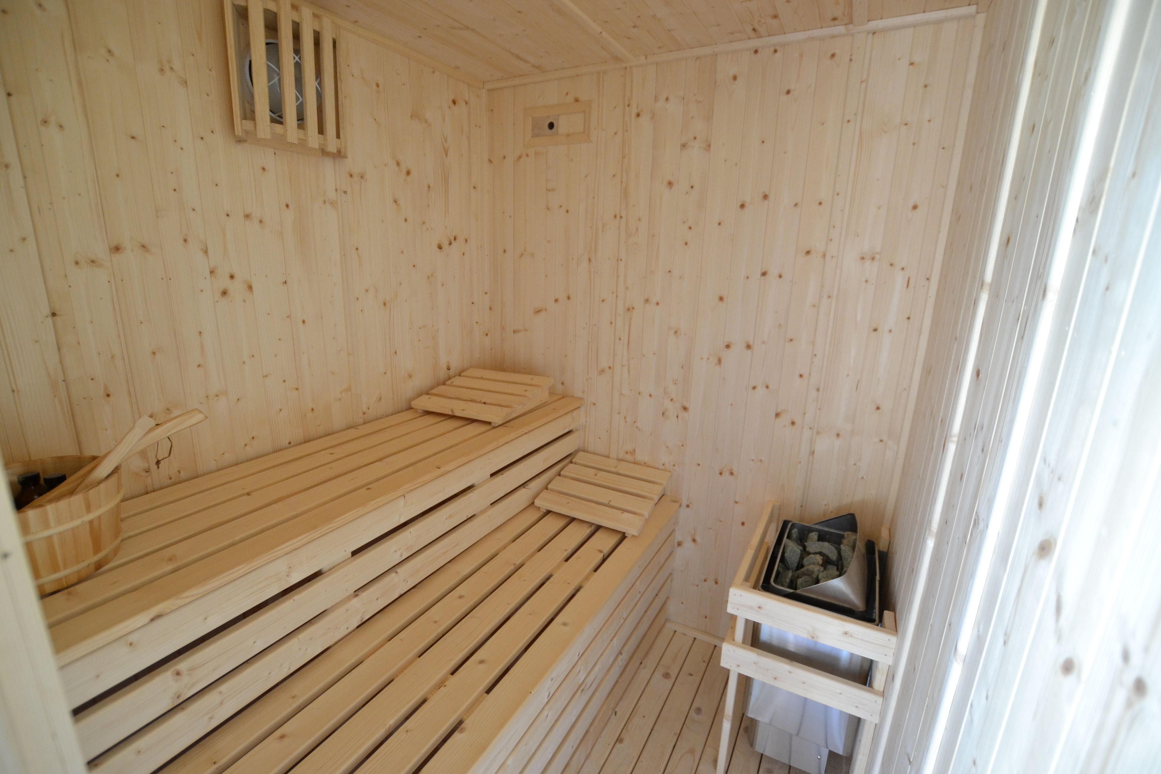 Una sauna de madera con bancos y un calentador pequeño.