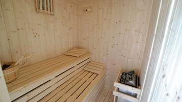 Una sauna de madera con bancos y un calentador pequeño.