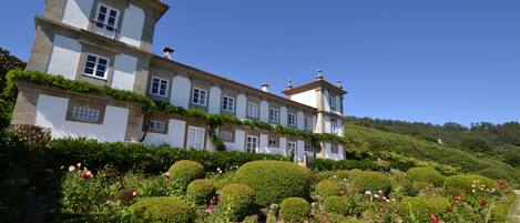 Stunning estate with a classic facade, surrounded by a beautifully manicured garden and rolling hills.