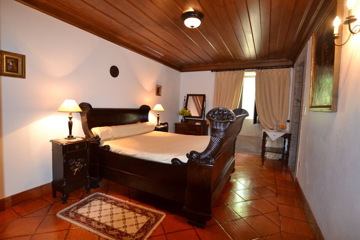 A bedroom with a wooden bed, nightstands, a mirror, and a window with curtains.