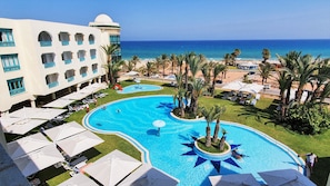 A resort with a large pool, palm trees, and a view of the ocean. - Mehari Hammamet Thalasso & SPA (Hammamet)