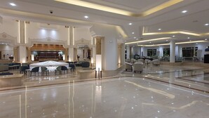 Un vestíbulo espacioso con mostrador de recepción, zona de estar y un elemento decorativo central.
