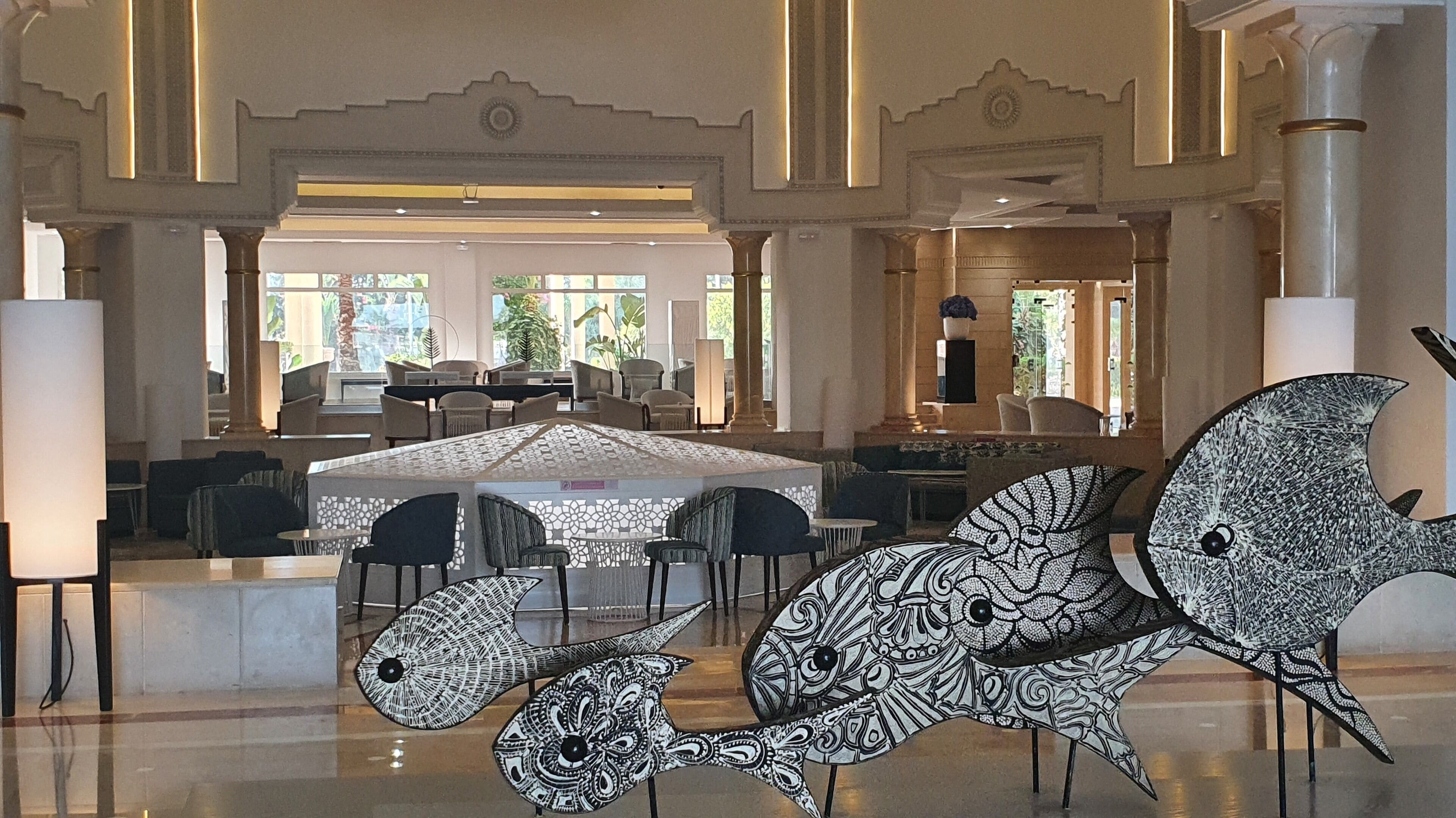 A spacious lobby with a central seating area, large windows, and a decorative bird sculpture.
