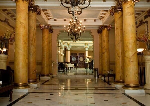 A grand lobby with marble columns, a chandelier, and a reception area. - Tunisia Palace (Tunis)