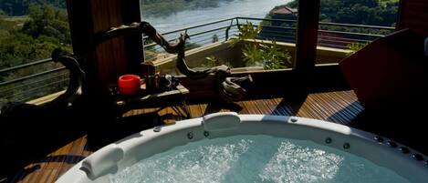 A hot tub with a view of a river and hills.