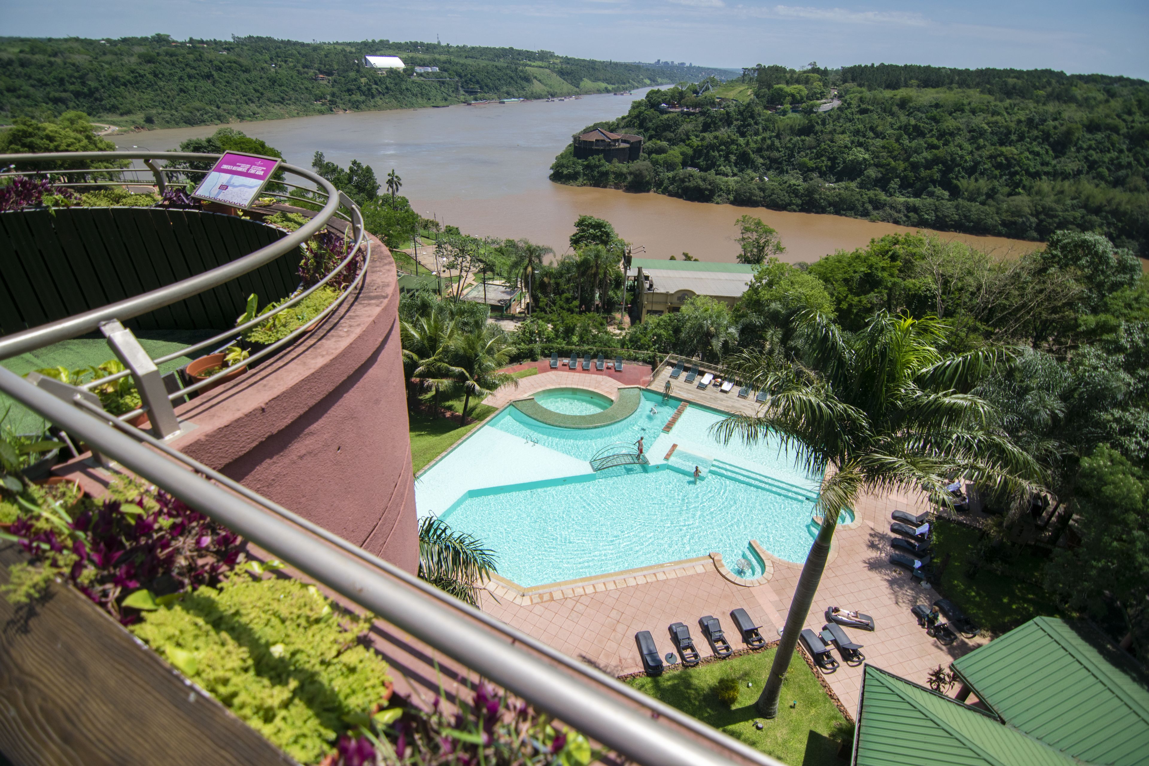 A view of a swimming pool with lounge chairs and a view of a river.