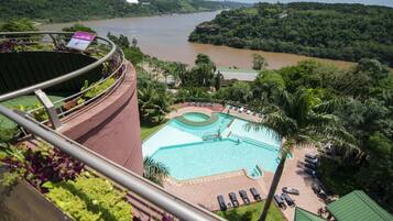 A view of a swimming pool with lounge chairs and a view of a river.