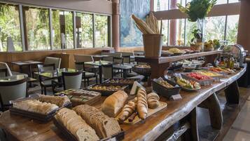 A buffet with various breads, pastries, and fruits.