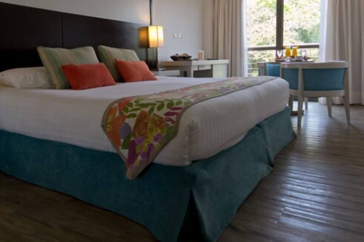 Une chambre d’hôtel avec un grand lit, un bureau, une chaise et une vue sur l’extérieur.