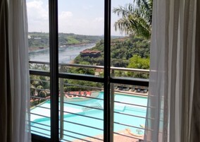 Vista de una piscina con un río y follaje en el fondo.