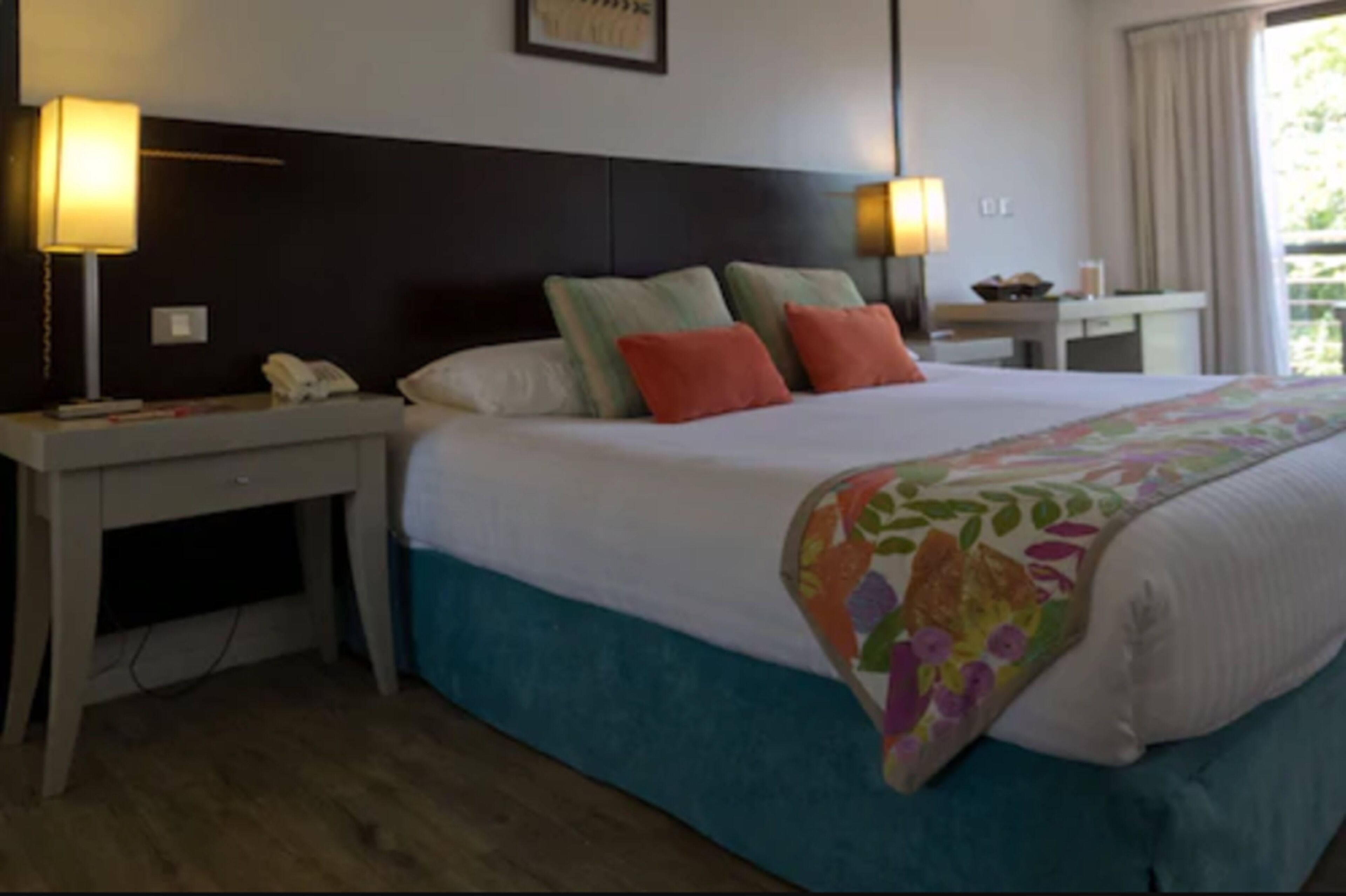 Una camera d'albergo con un letto, due comodini, una scrivania e una lampada.