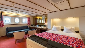 Une chambre d’hôtel avec un lit, un bureau, une chaise, un canapé et une fenêtre avec des rideaux.