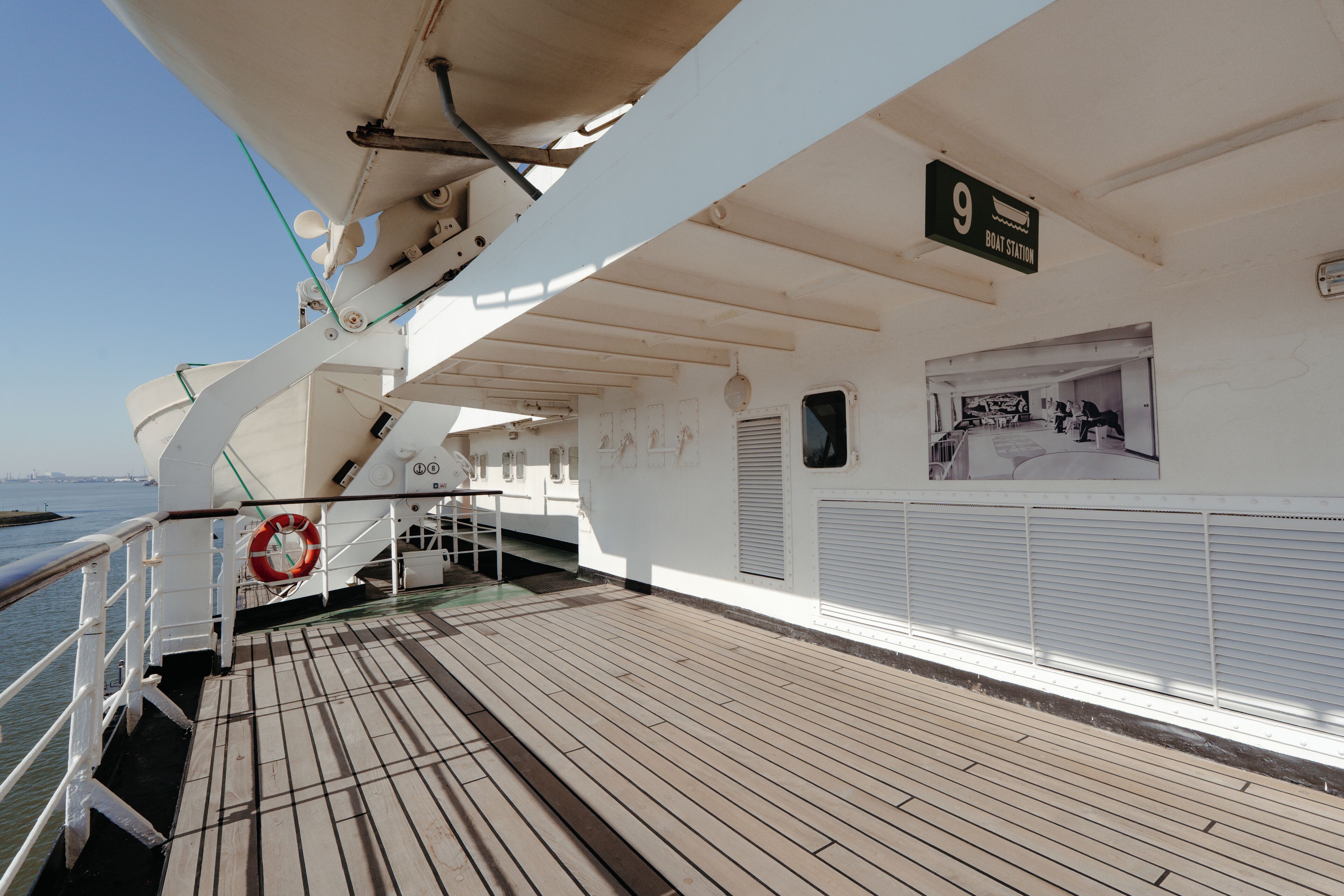 A boat deck with a lifebuoy, railing, and a sign indicating '9 Boat Station'.