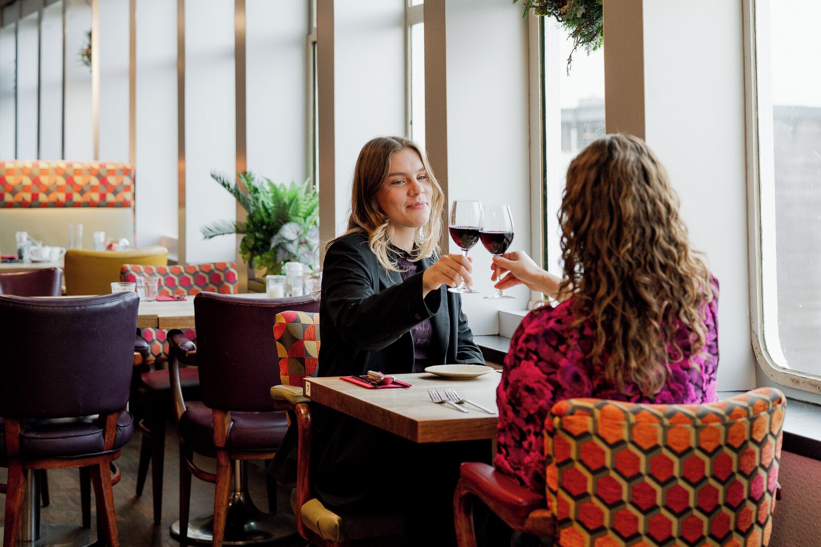 Two people dining at a table with a view of the city through large windows.
