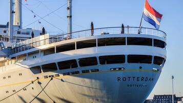 A large ship named 'Rotterdam' with multiple decks and a flag.