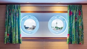 Une salle de bain avec deux miroirs ronds, un lambris en bois et des rideaux verts à motifs floraux.