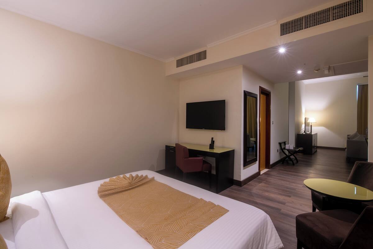 Een hotelkamer met een bed, bureau, stoel, televisie en een kleine tafel.