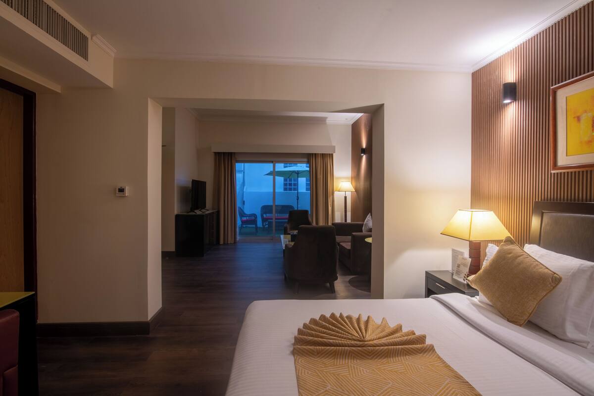 Hotelkamer met een groot bed, een bureau met lamp, een televisie en uitzicht naar buiten.