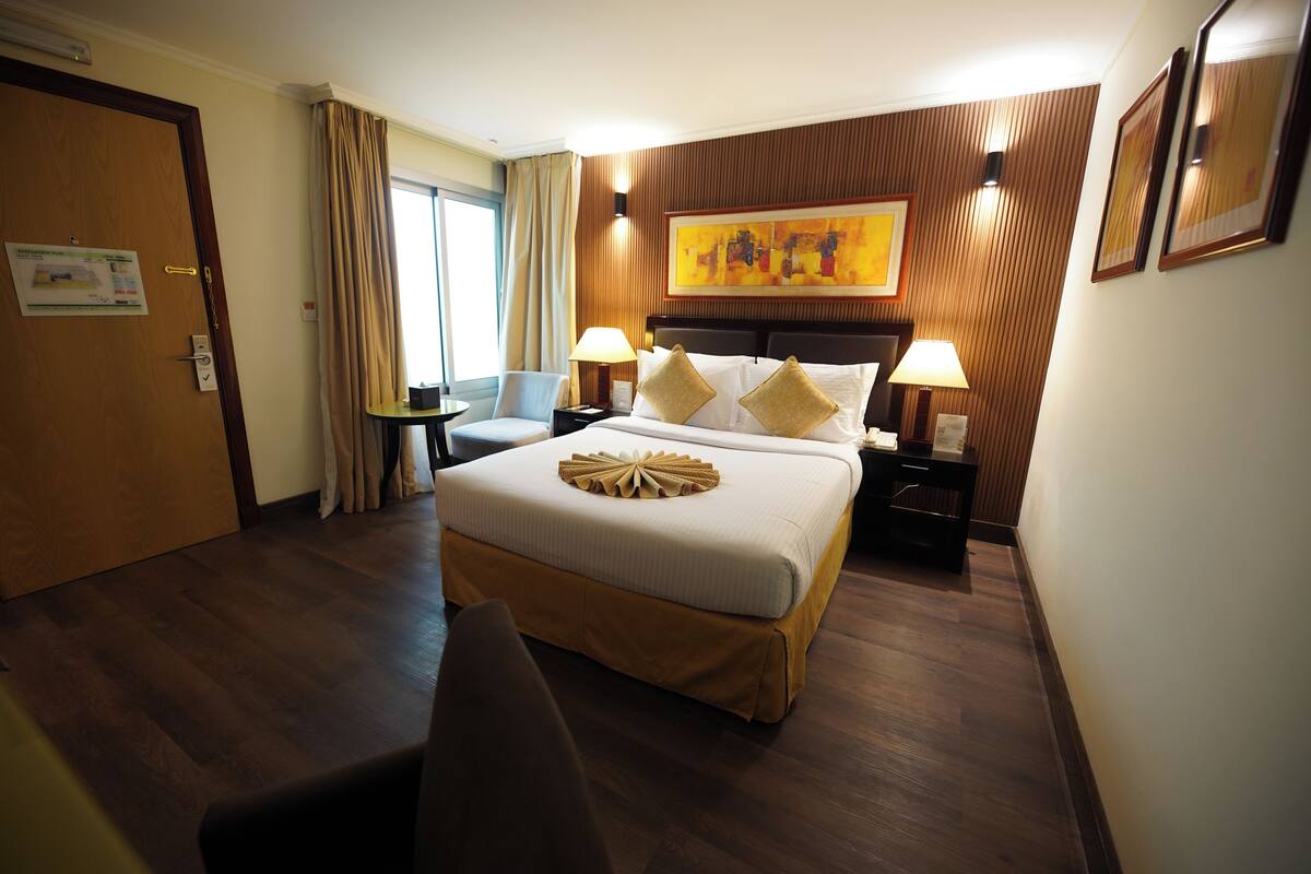 Een hotelkamer met een groot bed, twee nachtkastjes, een bureau en een stoel.