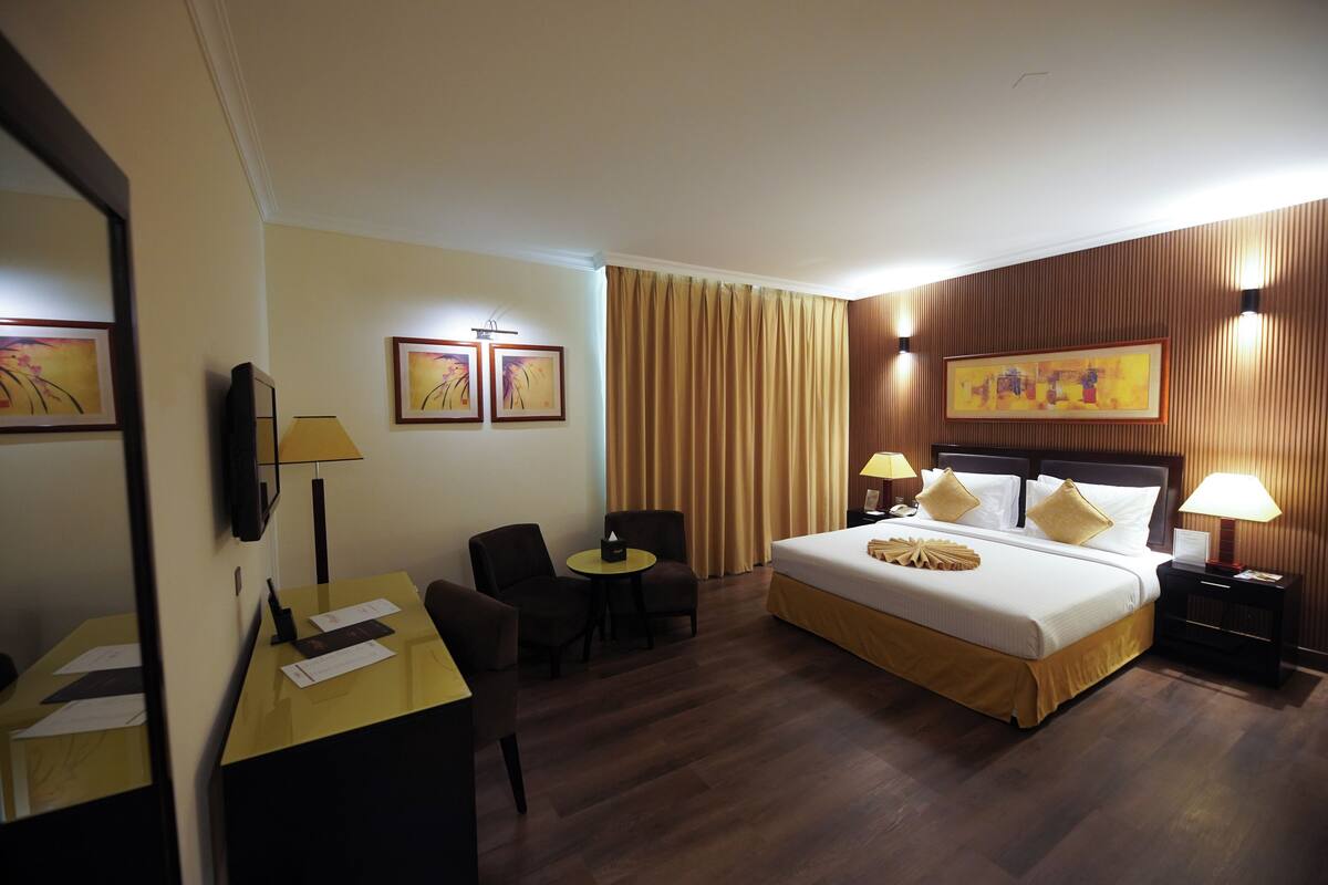 Een hotelkamer met een bed, bureau, stoelen en kunstwerken aan de muur.