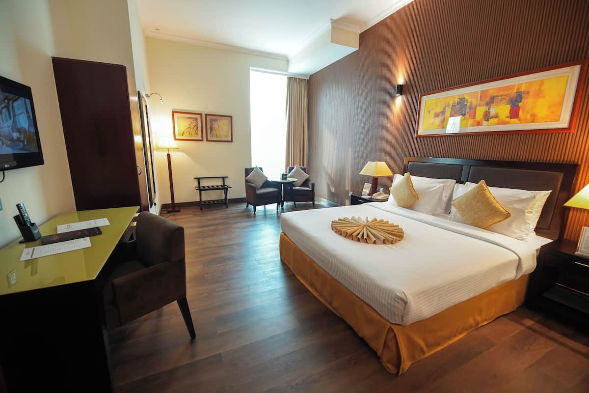 Een hotelkamer met een groot bed, een bureau, een stoel en een televisie.