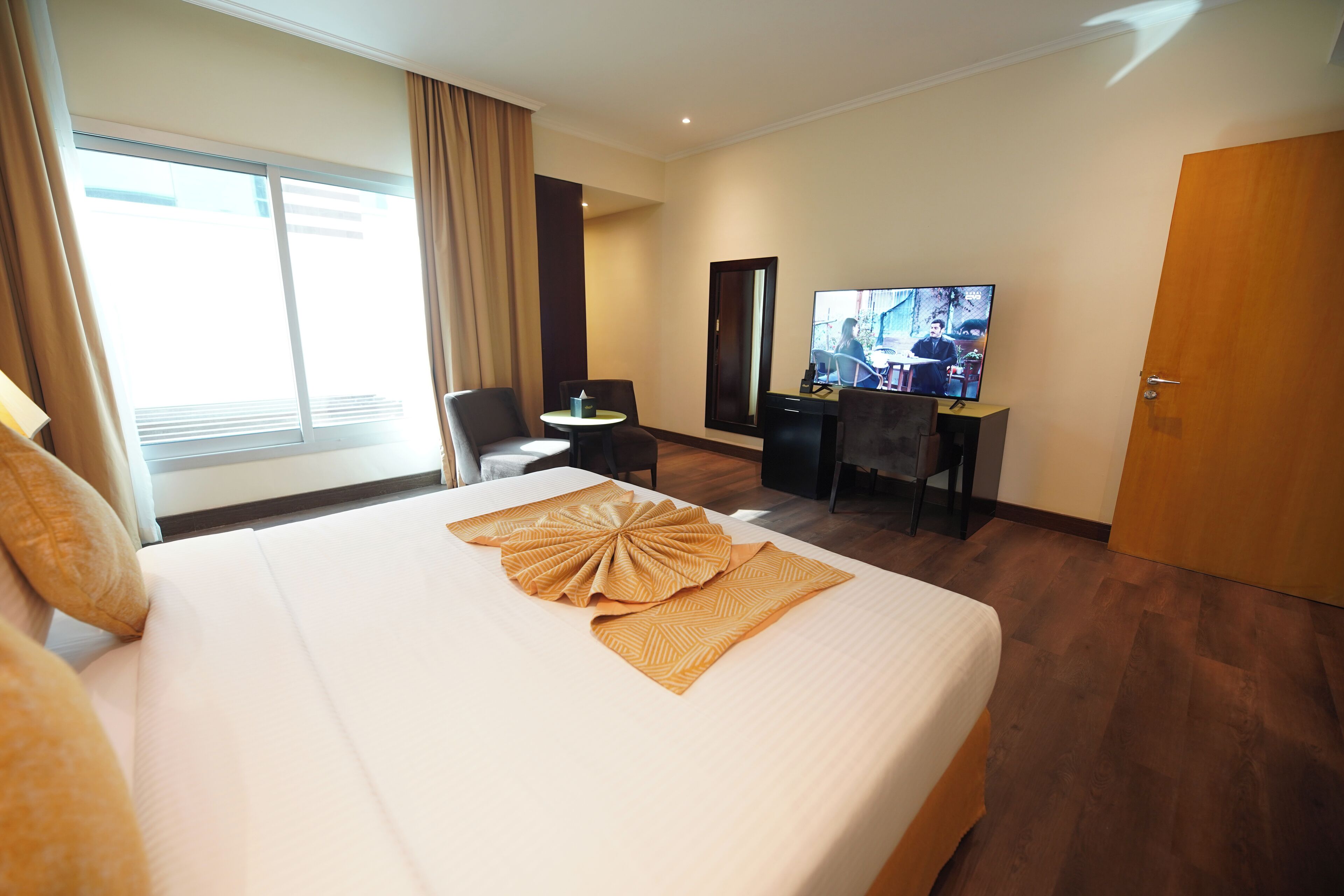 Une chambre d’hôtel avec un grand lit, un bureau, une télévision et une porte.