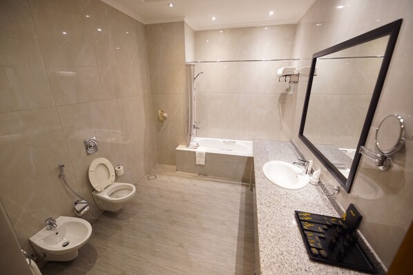 Un baño moderno con una bañera, dos inodoros, un lavabo y un espejo grande.
