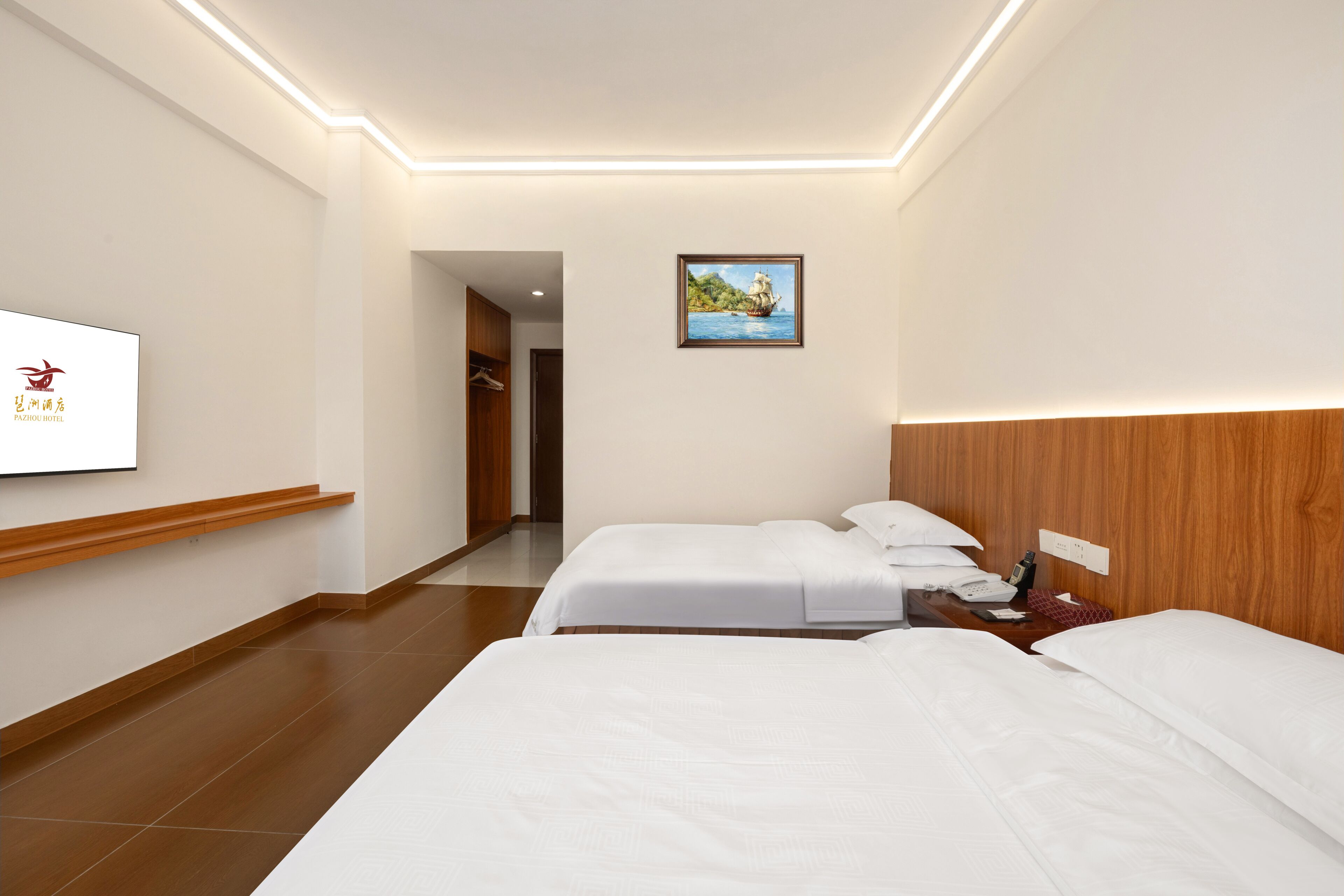 A hotel room with two beds, a wooden headboard, a painting on the wall, and a TV on the wall.