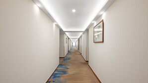 A long, narrow hallway with a carpeted floor, white walls, and framed artwork on the right. - Pazhou Hotel (Guangzhou)