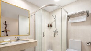 A modern bathroom with a glass-enclosed shower, a sink with a mirror, and a toilet. - Pazhou Hotel (Guangzhou)