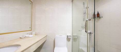 Une salle de bain moderne avec une douche à parois de verre, des toilettes blanches et un meuble-lavabo beige agrémenté d’un miroir.