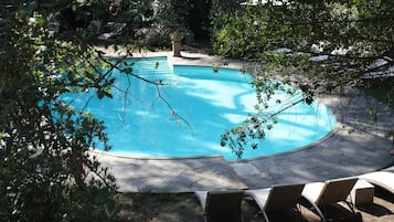 Una piscina al aire libre, sillones reclinables de piscina