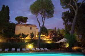 A poolside area with lounge chairs, a building with a balcony, and trees. - Borgo Dolciano (Chiusi)