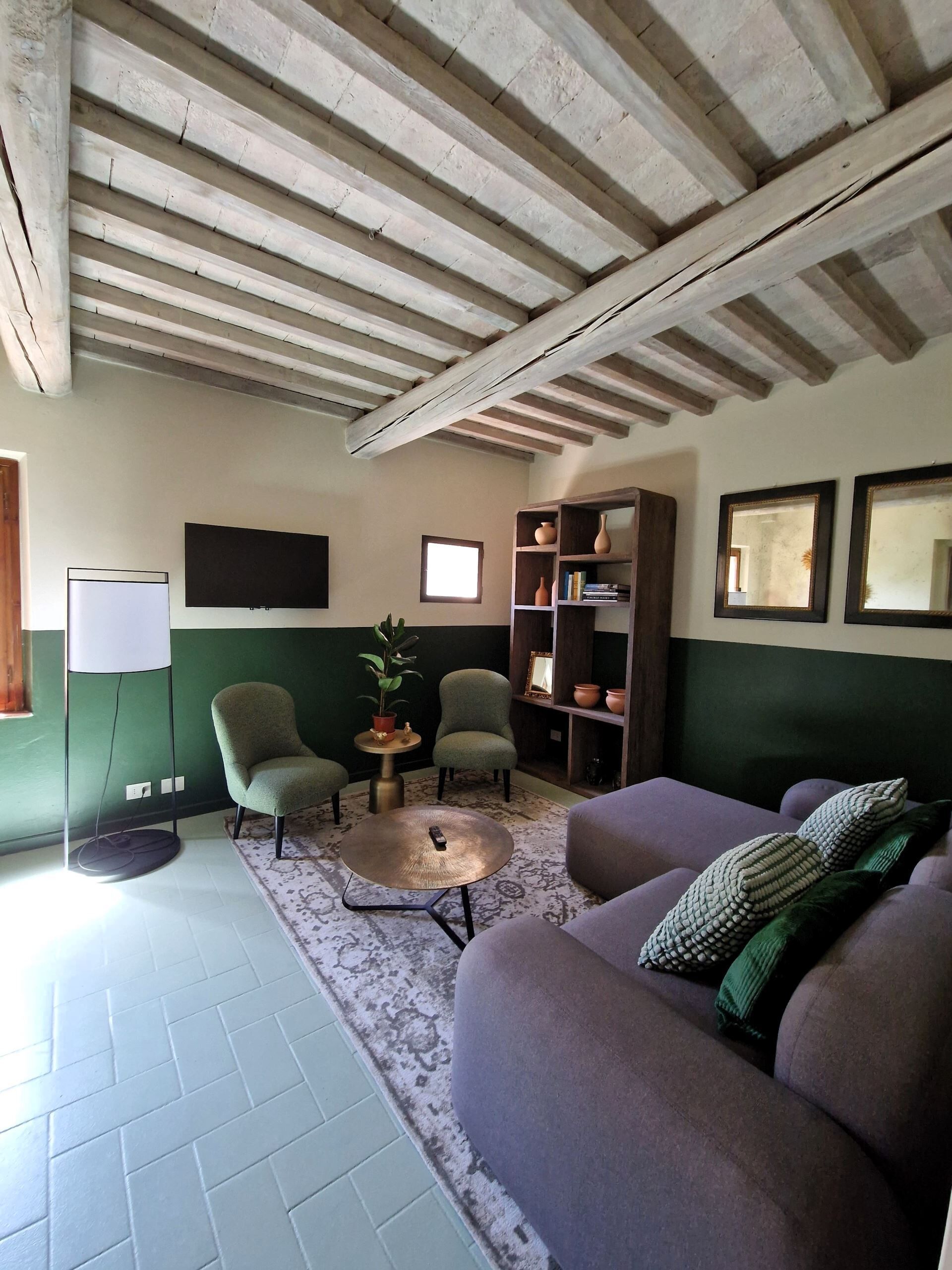 A cozy living room with a green sofa, a round coffee table, and a bookshelf.
